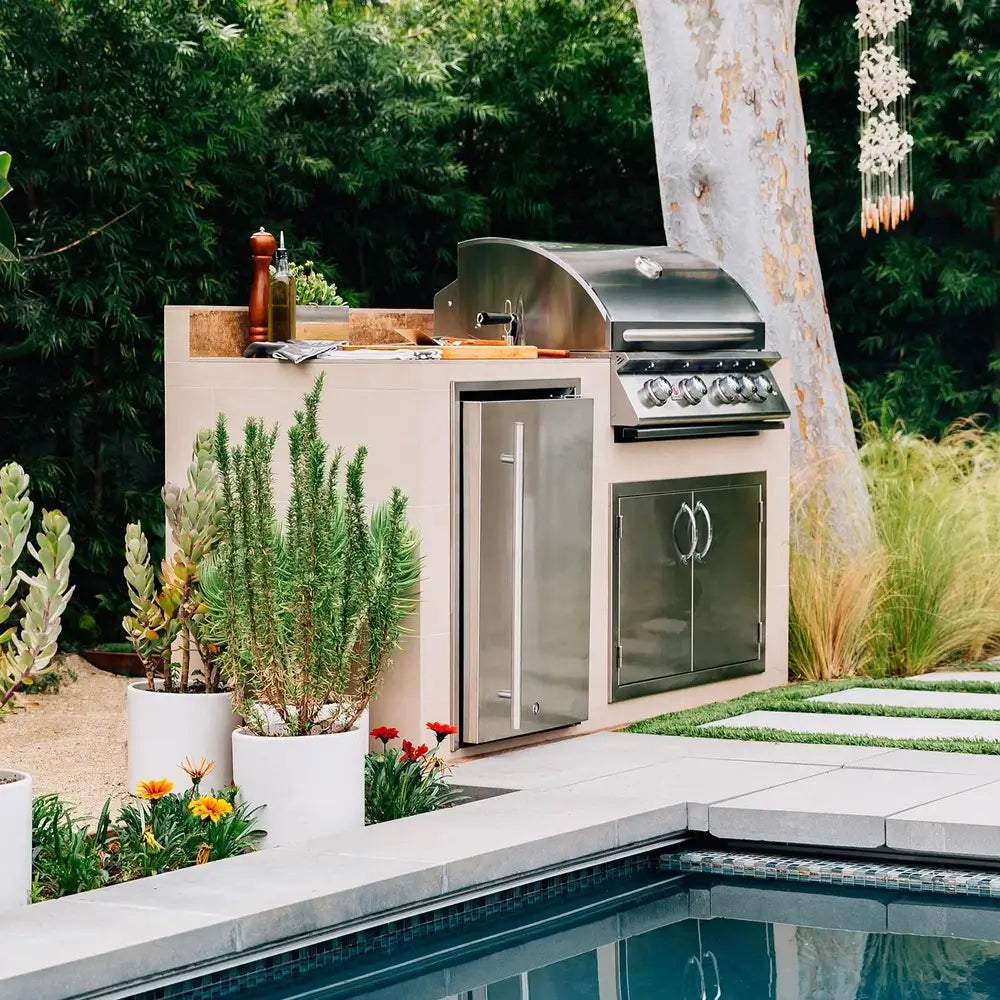 Outdoor kitchen with built-in stainless steel Summerset gas grill and refrigerator beside pool