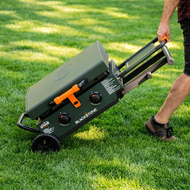 Man pulling the Blackstone 22" tabletop griddle with collapsible legs and wheels for easy transport
