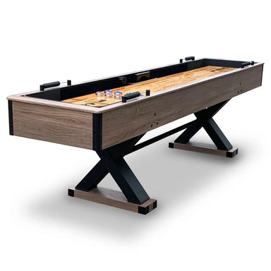 Hathaway Excalibur 9-ft shuffleboard table featuring a driftwood melamine finish, black X-frame legs, and built-in scoring systems.