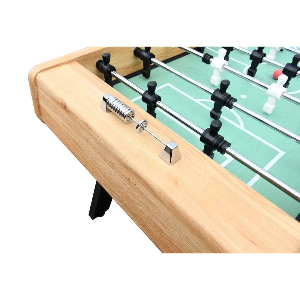 Detailed view of chrome-plated manual score counter mounted on a light oak foosball table with green field and player rods.
