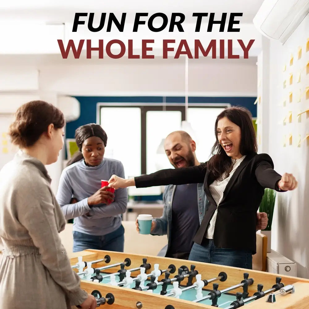 Diverse group of four adults enjoying a foosball match indoors, smiling and celebrating around a light oak foosball table with black and white player figures.