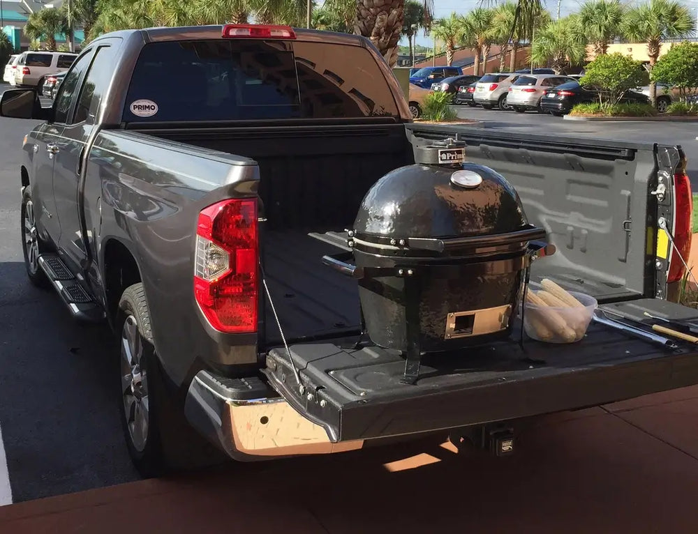 Kamado-style charcoal grill ready for grilling in truck bed