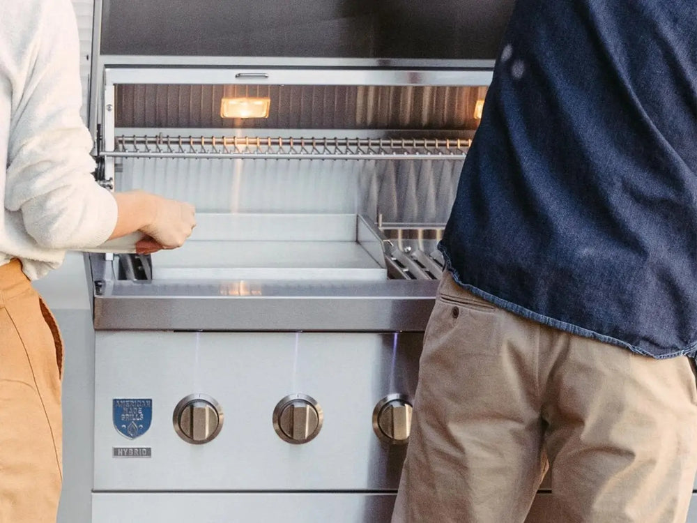 Two people preparing to cook on open stainless steel hybrid grill