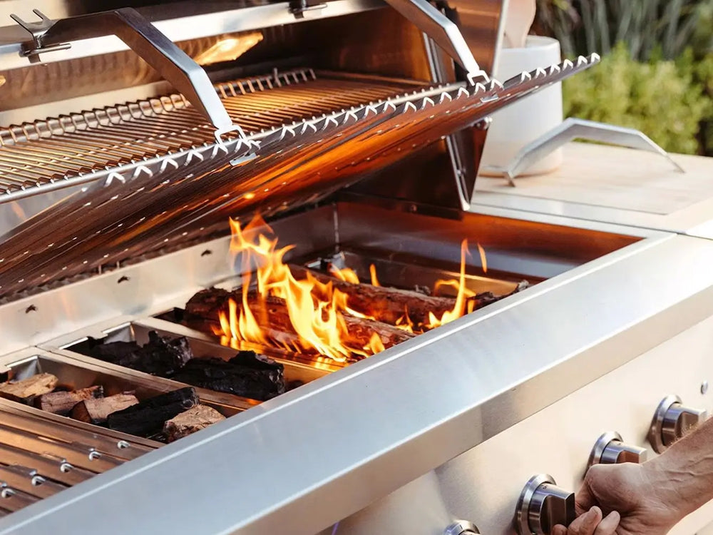 Person lighting a premium stainless steel outdoor grill with wood and charcoal