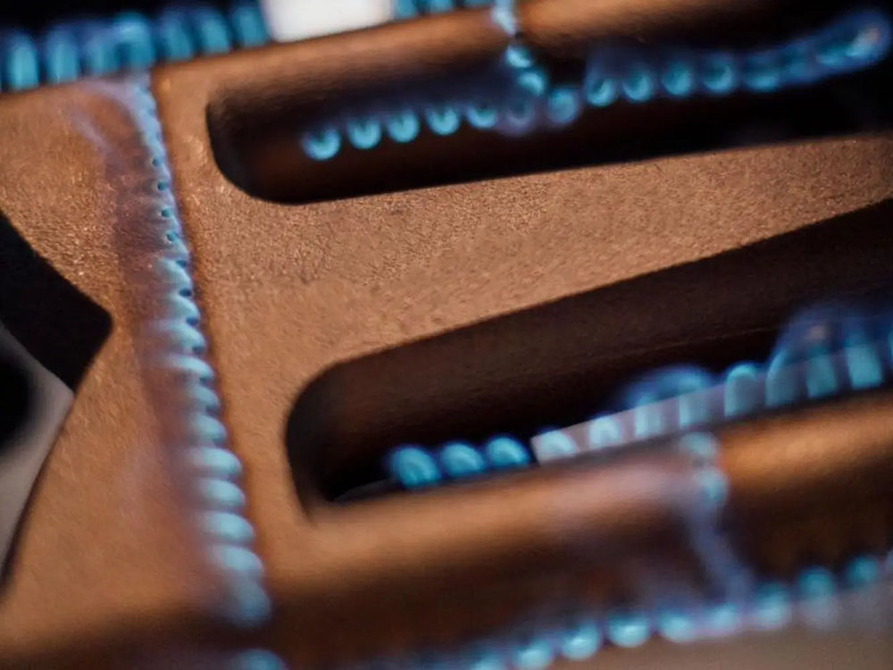 Close-up of blue flames on cast brass gas grill burner