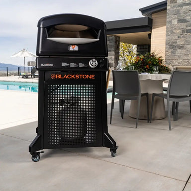 Blackstone propane pizza oven with rolling stand placed beside outdoor patio and swimming pool