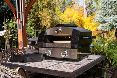 Blackstone outdoor portable pizza oven on tiled patio table surrounded by fall foliage