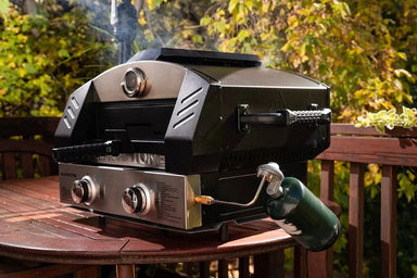 Rear side of Blackstone portable gas pizza oven connected to 1 lb propane tank on round patio table