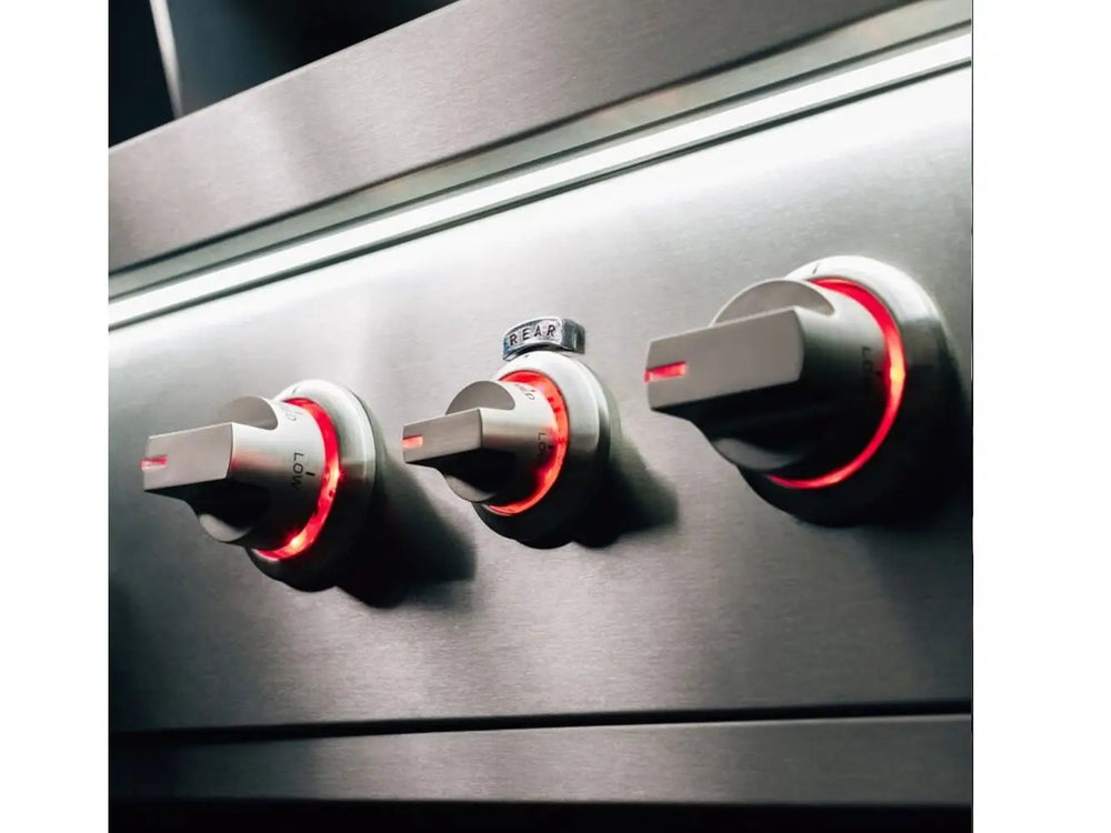 Three stainless steel grill control knobs illuminated with red LED lights.