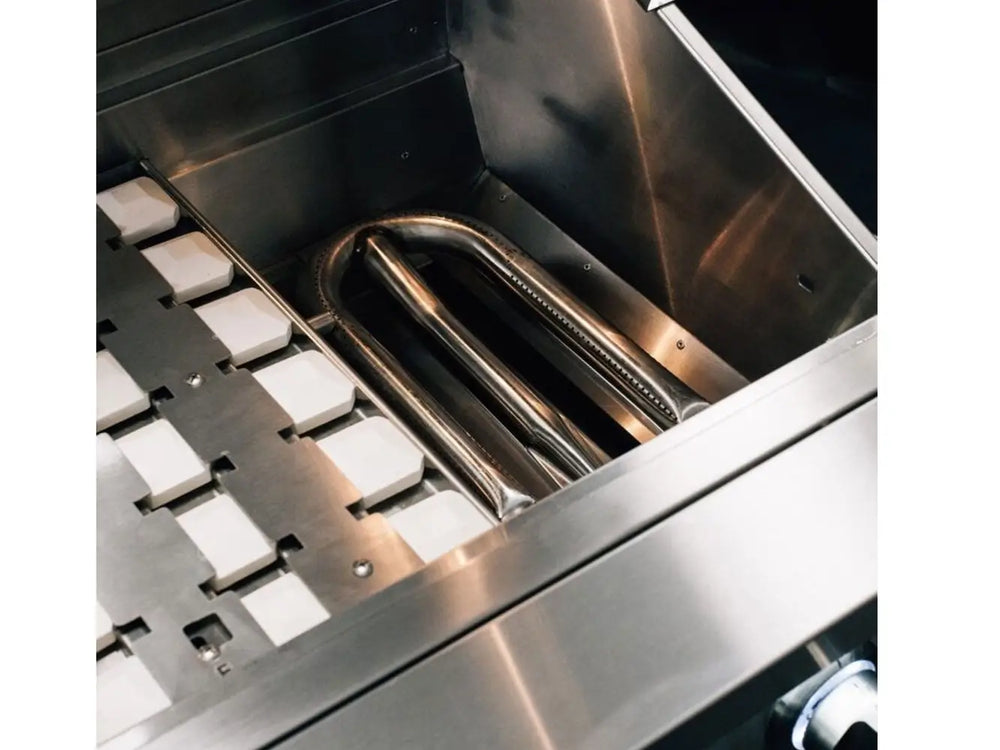 Stainless steel U-burner and ceramic briquette trays inside outdoor gas grill firebox.