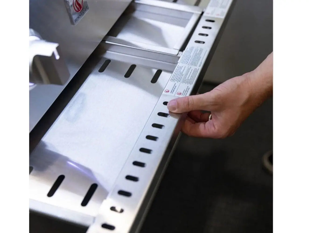 Hand adjusting stainless steel heat zone divider inside premium gas grill.