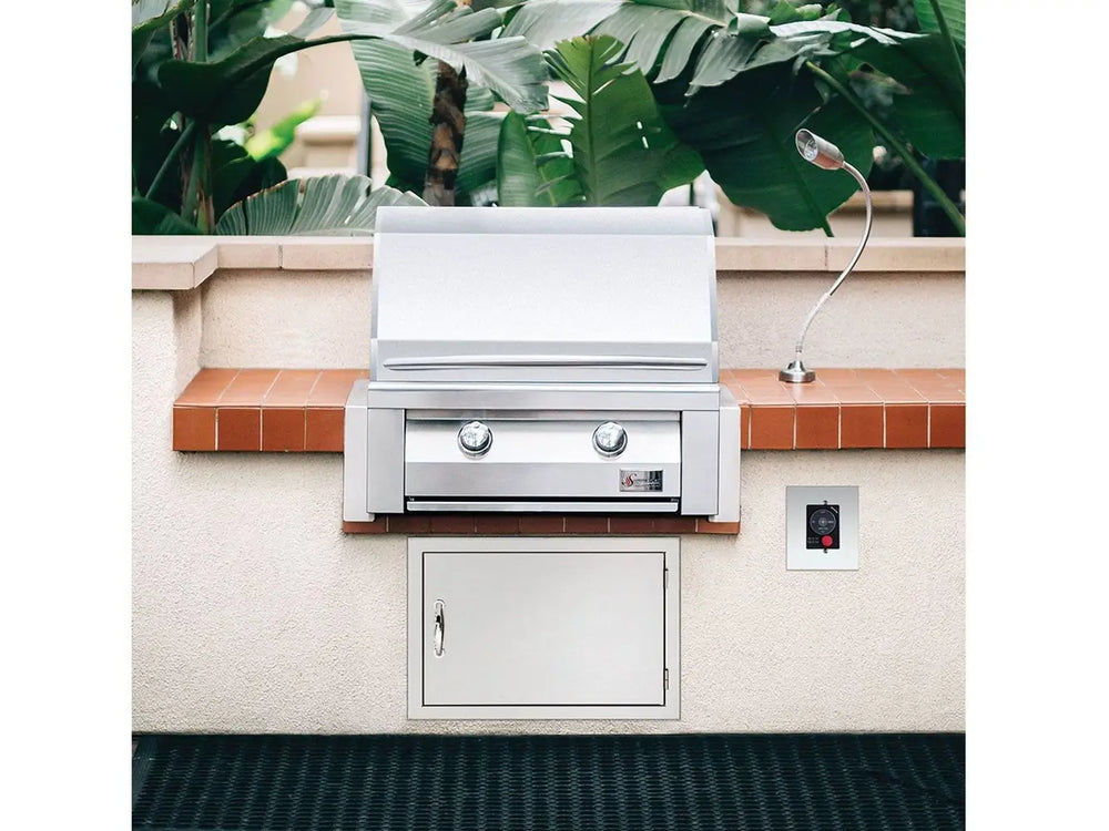 Built-in stainless steel gas grill with hood closed, set into tiled outdoor kitchen island.