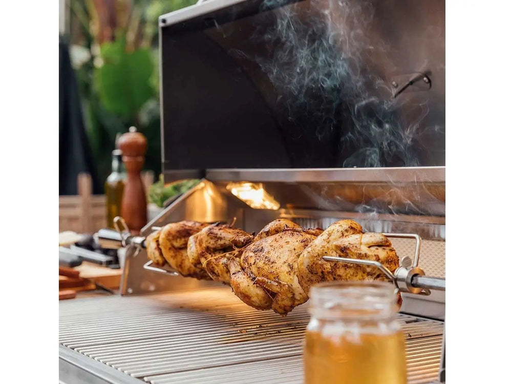 Rotisserie cooking whole chickens on a stainless steel outdoor gas grill.