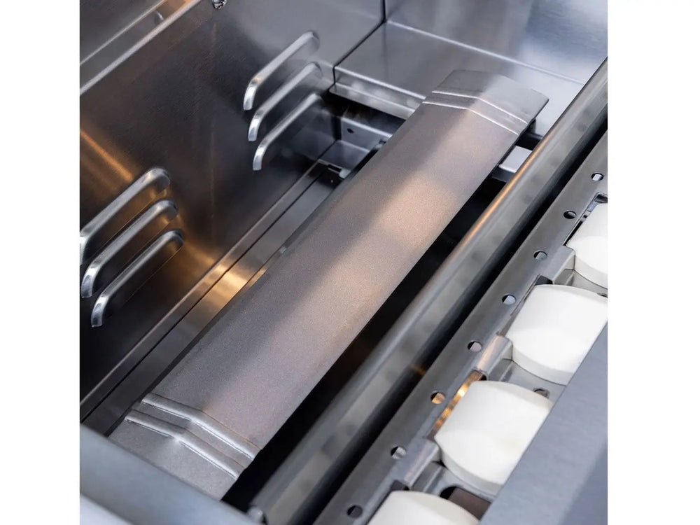 Stainless steel heat shield covering ceramic briquettes inside a gas grill.