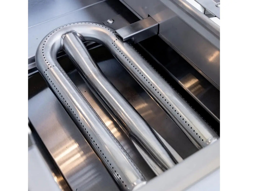 Stainless steel U-burner without flame inside outdoor grill firebox.