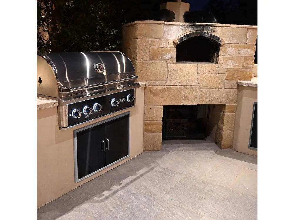 Wildfire 42-Inch Built-In Gas Grill installed in outdoor kitchen with stone pizza oven beside it