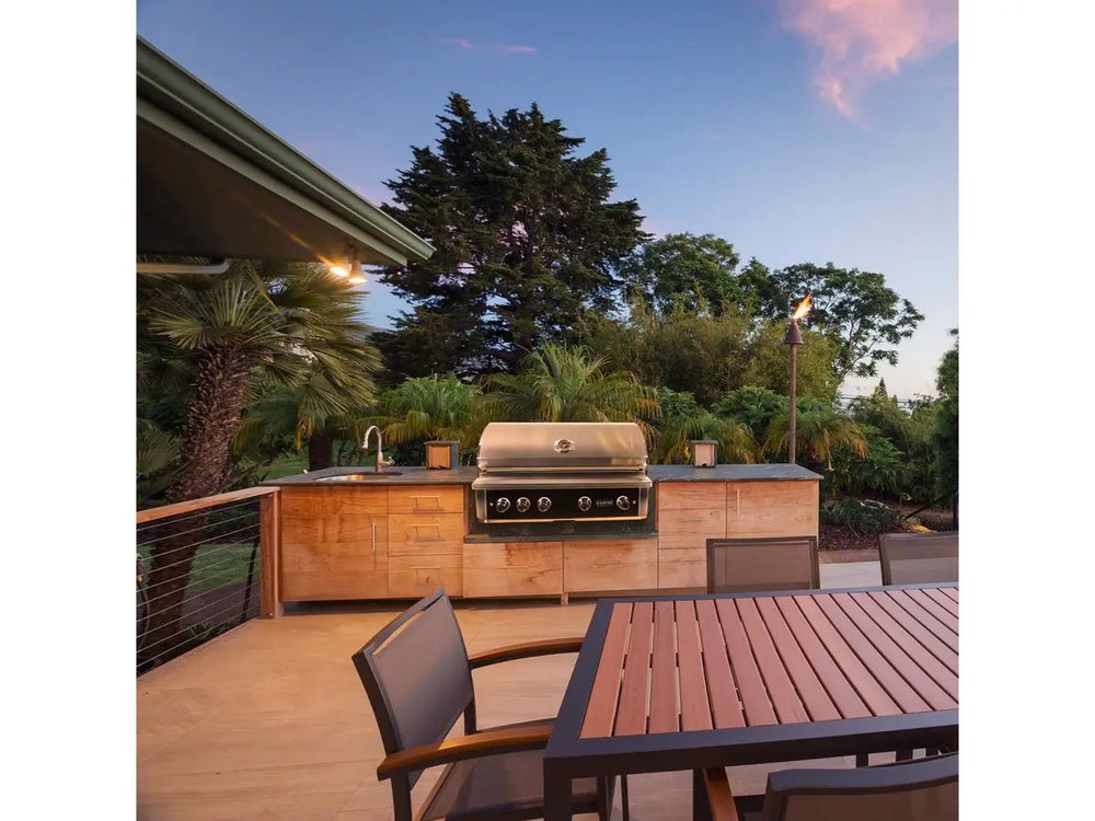 Wildfire 42-Inch Built-In Gas Grill in modern outdoor kitchen island with dining table and sunset view