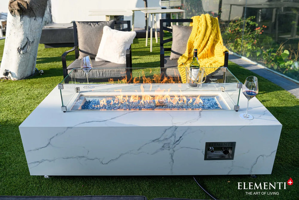 High-end patio setting featuring the Carrara Bianco fire pit table as a centerpiece, paired with designer white lounge chairs and a modern poolside view.