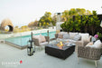Modern outdoor living area featuring the Bulgaria Black rectangular gas fire pit table, a designer woven bird's nest chair, and a classic silver trailer in a poolside setting.