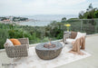 Elementi Boulder fire table equipped with a circular tempered glass wind guard for flame protection on a windy balcony.