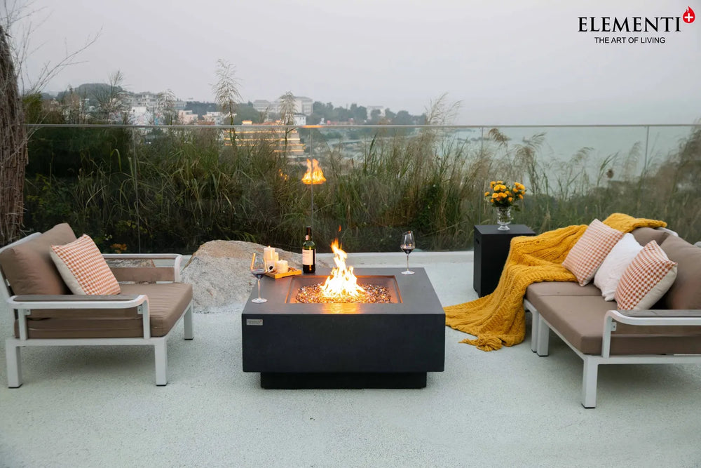 Elementi Plus OFG413DG Bergen slate black gas fire table on a luxury poolside patio.