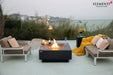 Elementi Plus OFG413DG Bergen slate black gas fire table on a luxury poolside patio.