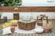 Rustic patio featuring an Elementi Manchester OFG145RW Fire Table 42" Red Wood with outdoor chairs and greenery.