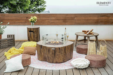 Rustic patio featuring an Elementi Manchester OFG145RW Fire Table 42" Red Wood with outdoor chairs and greenery.