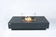 Elementi Plus Cannes fire table with glass wind guard and active flame.