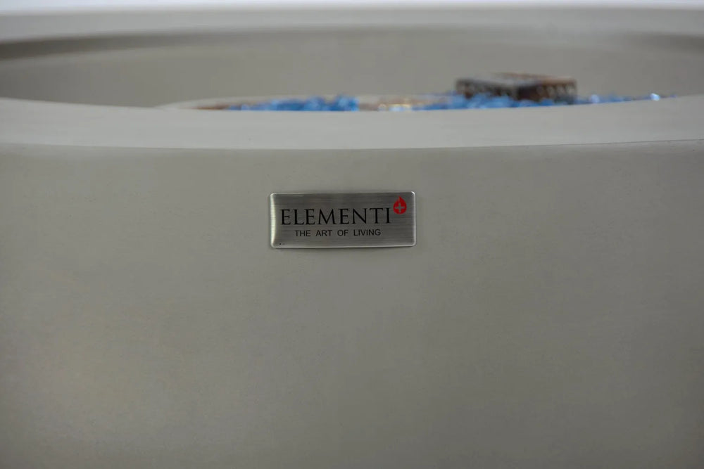 Close-up of Elementi “The Art of Living” logo badge on light gray Colosseo fire table