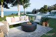 Elementi Plus Nimes dark gray fire table in outdoor lounge with sofa seating and ocean view.