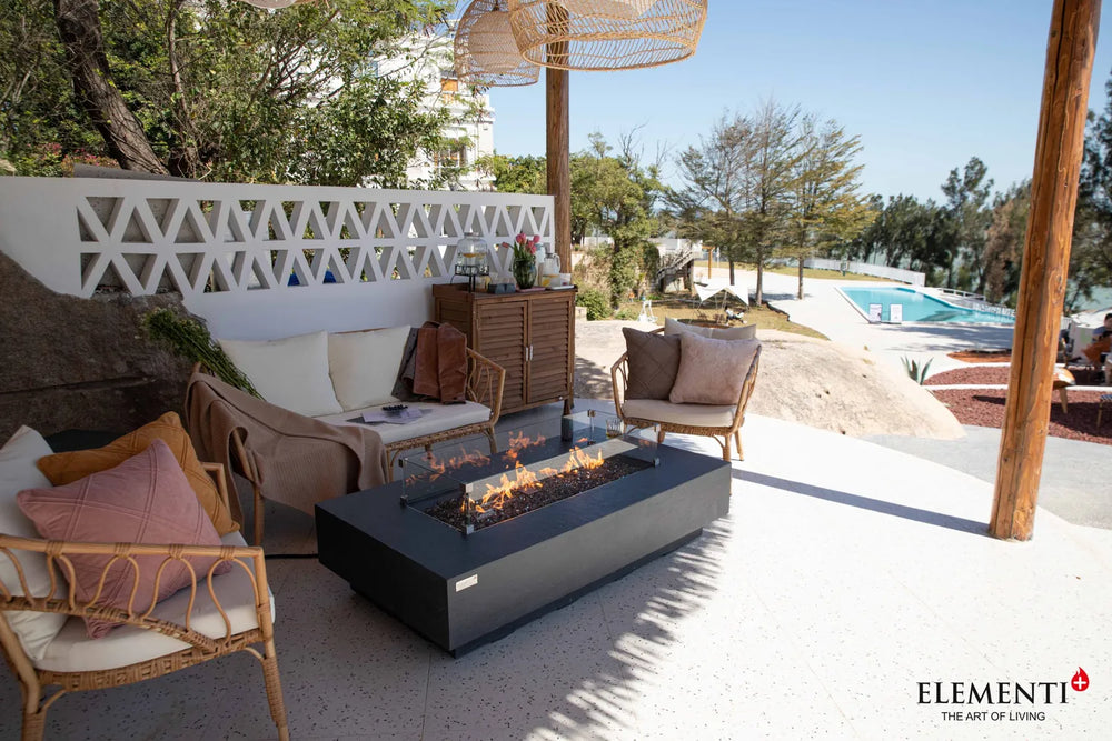 Elementi Plus Positano dark gray fire table in covered outdoor lounge with wicker seating.