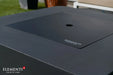 Elementi branded burner cover lid on dark gray fire table showing smooth tabletop surface.