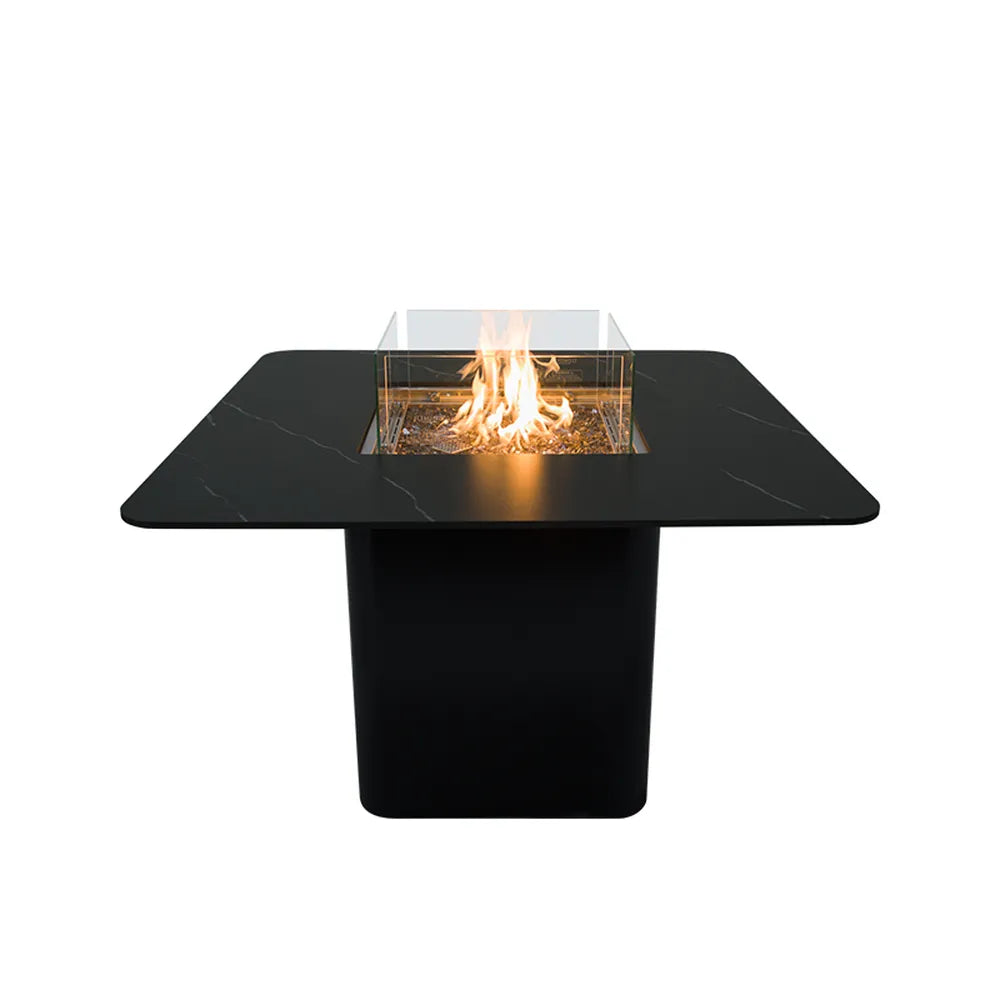 Studio shot of the 60,000 BTU Elementi Plus Brugge Bulgaria Black dining-height fire table on a white background, featuring a lit linear flame and dark glass fire media.