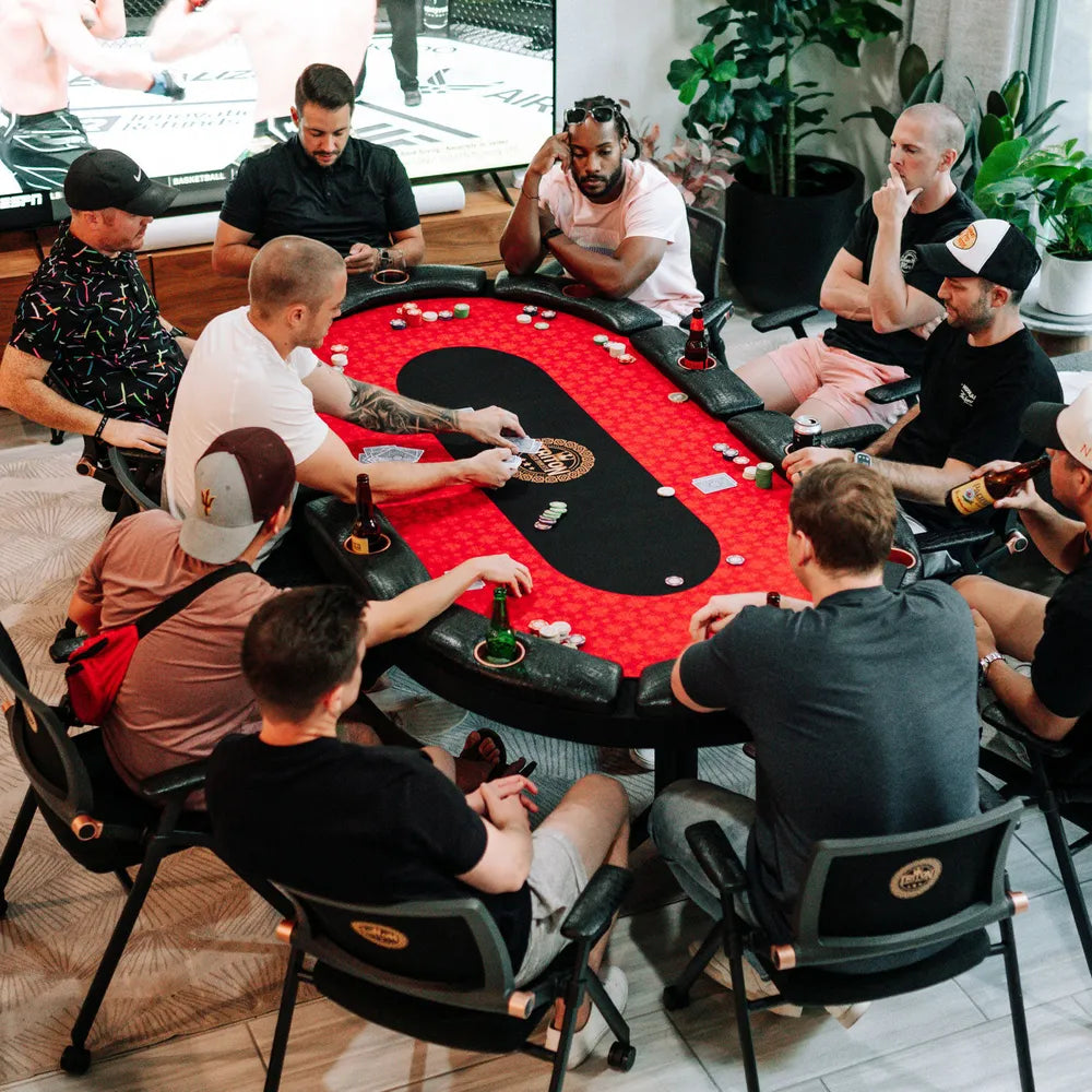 Group of players gathered around the Triton 90-inch premium 10 player folding poker table with red felt, black center lane, padded armrests, and built-in cup holders.