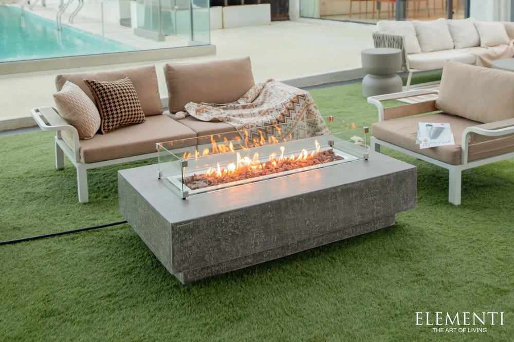 Dark gray Elementi Hampton OFG139DG 56" Fire Table with a tempered glass wind guard.