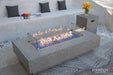 Elementi Plus Riviera fire table with glass wind guard and blue fire glass on patio.