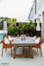 Modern patio setting with the lit gray Elementi OFG201 Sonoma Dining Fire Table and scenic backyard view.