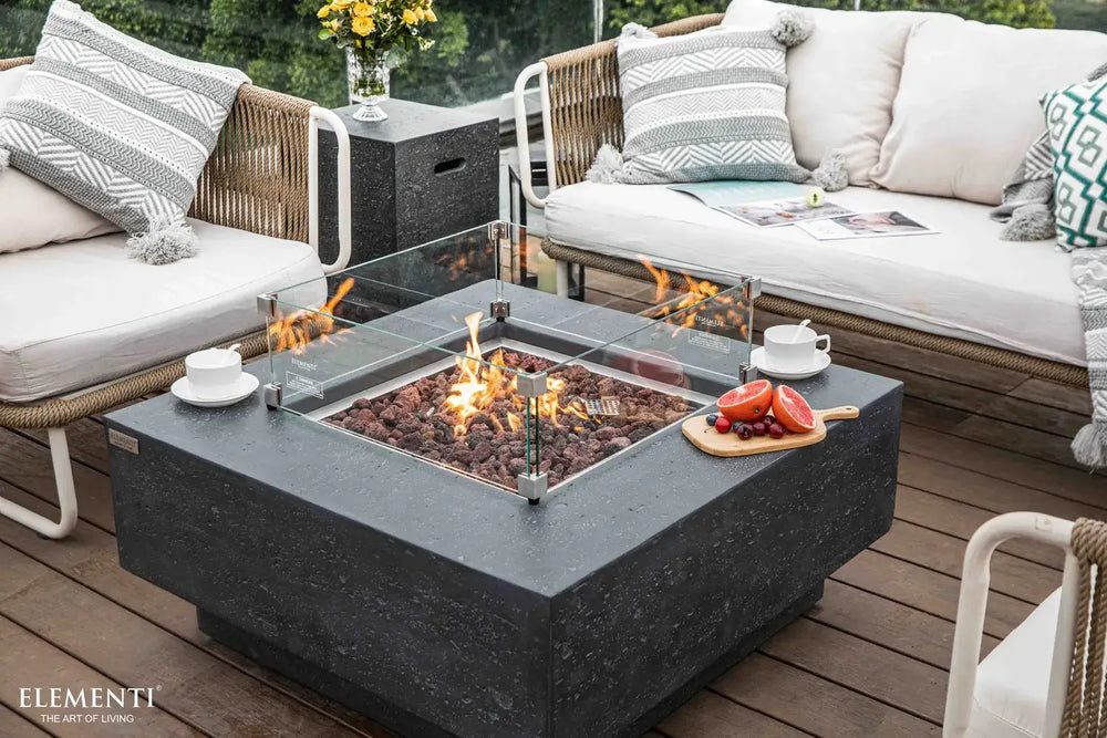 Elementi Manhattan fire table equipped with a clear tempered glass wind guard for flame protection on a windy patio.
