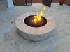 A Travertine TessaRai 46" Round Gas Fire Pit with active flames and black lava rock media installed on a modern light-colored stone patio.