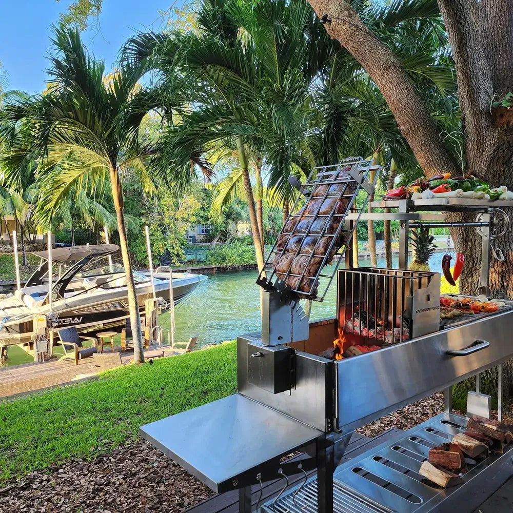 Tagwood BBQ06SS Argentine grill outdoor setup beside canal with palm trees and boat dock