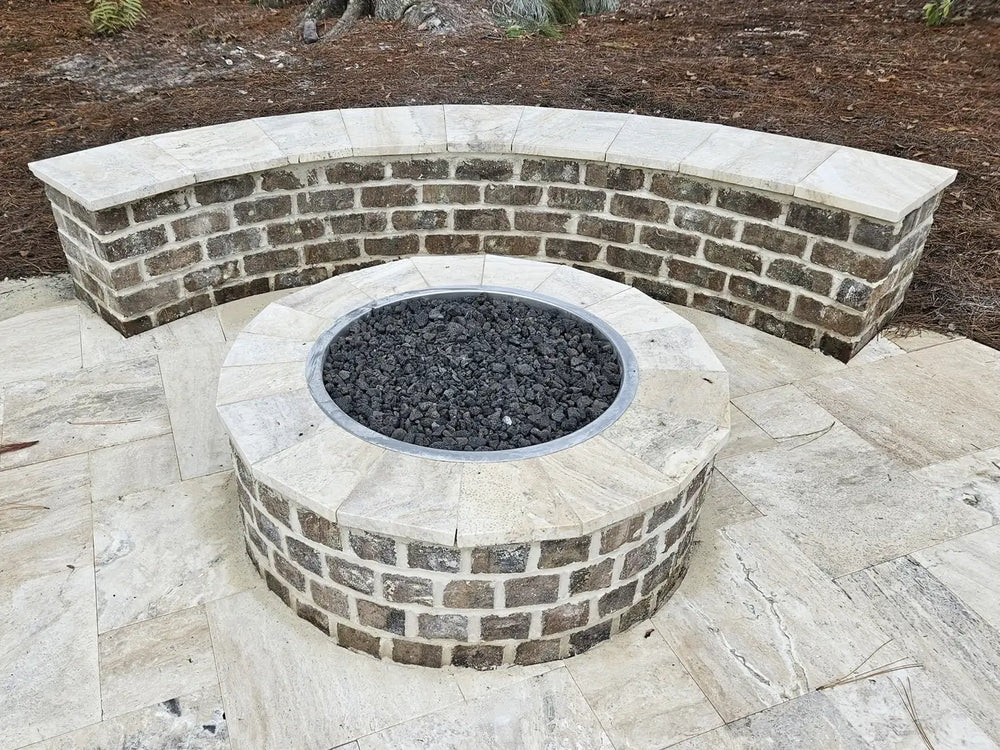 Elevated view of a Travertine TessaRai 46" Round Gas Fire Pit with a matching curved stone seating wall on a travertine tile patio.