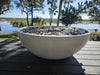 Travertine TessaRai 40 inch Patio Fire Pit Kit with black and clear fire glass on waterfront deck in daylight