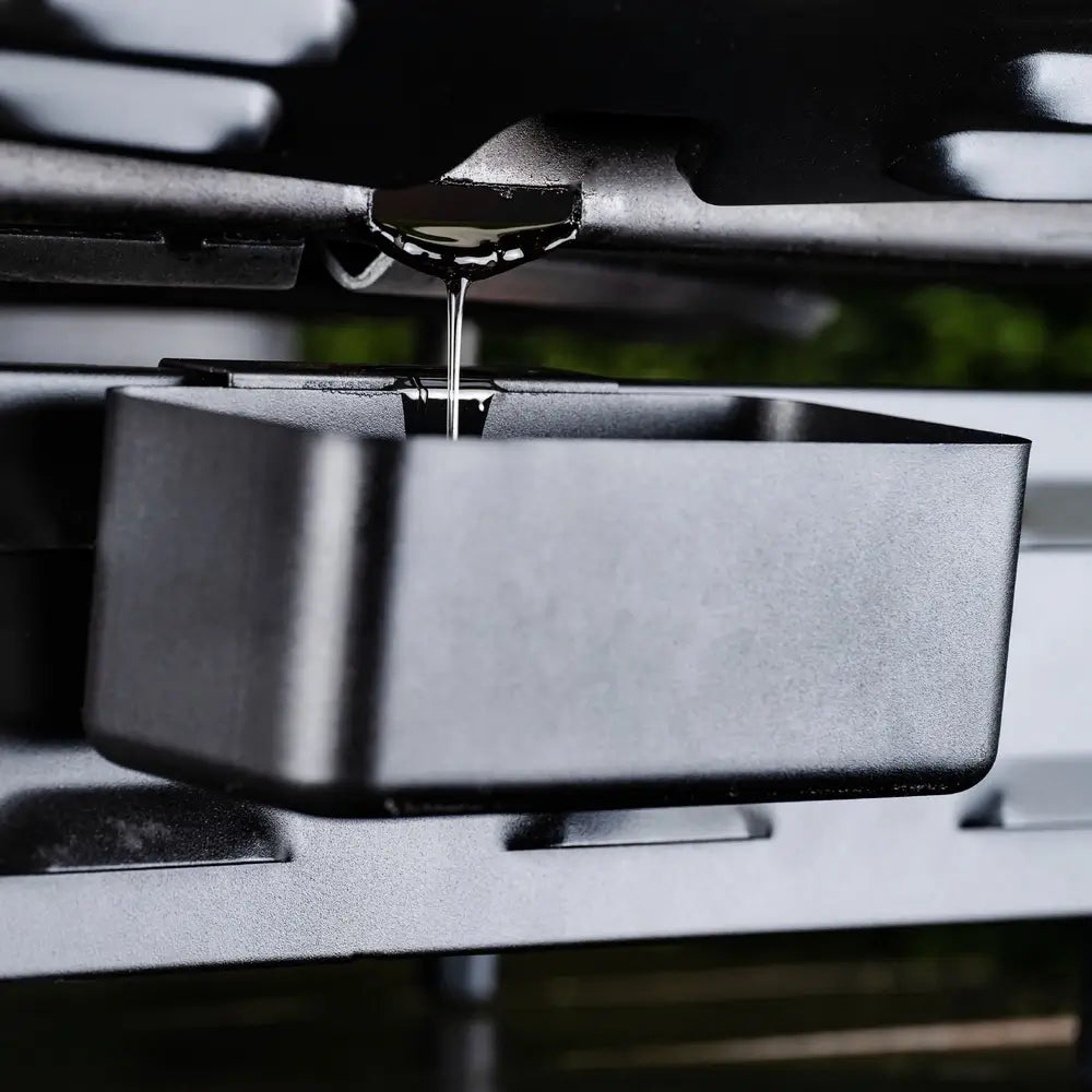 Close-up of Blackstone 17-inch griddle's rear grease management system with drip tray catching oil for easy cleanup