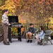 Outdoor patio cooking with Blackstone 22" portable griddle and hood while kids relax on wicker chairs