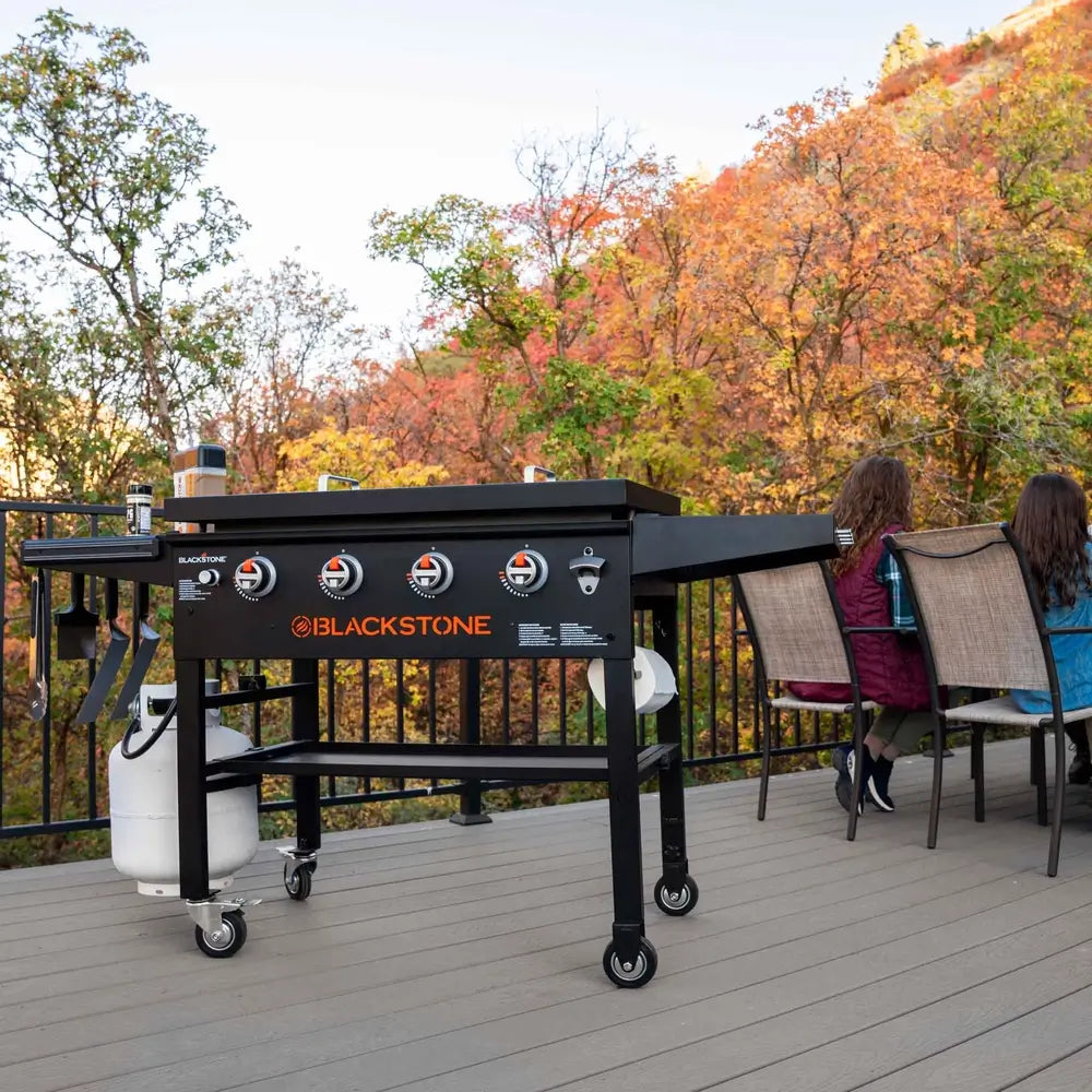 Blackstone 36-inch griddle on deck with scenic forest view and seated family – stylish and functional outdoor cooking centerpiece