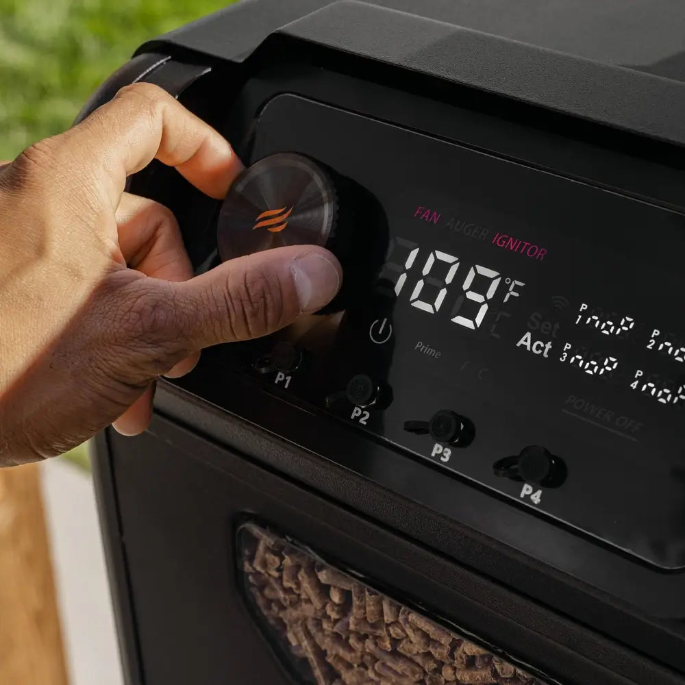 Hand adjusting temperature dial on Blackstone 900 Pellet Grill digital control panel with wood pellets in visible hopper