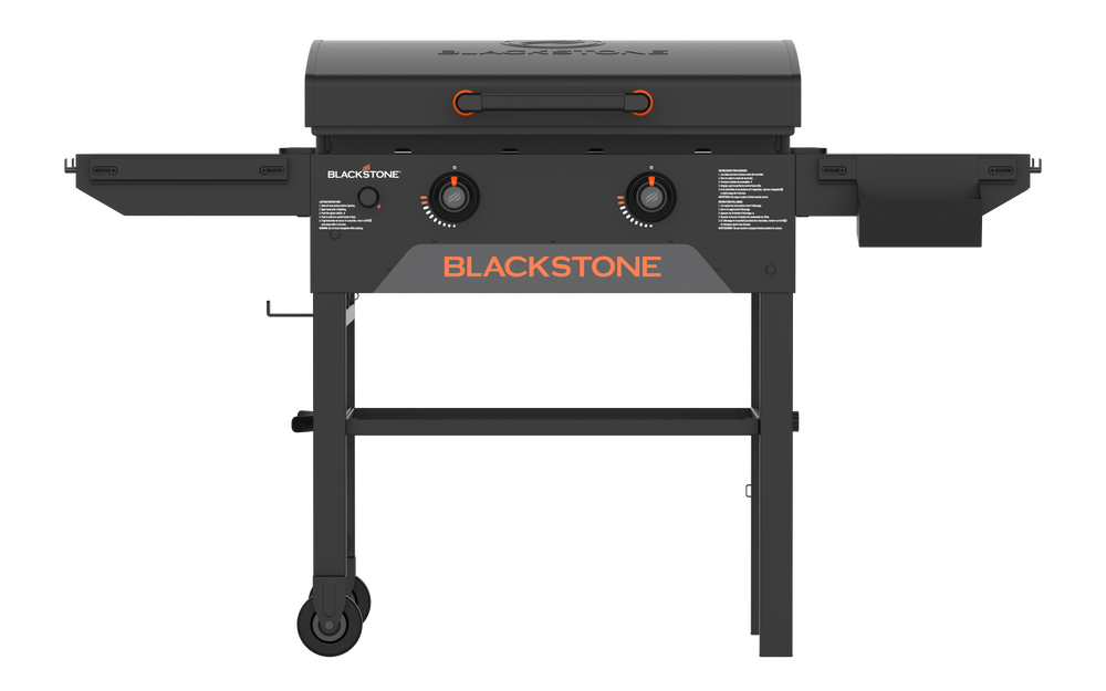 Blackstone 28-inch griddle grilling burgers and vegetables on dual heat zones with stainless hood and side shelves