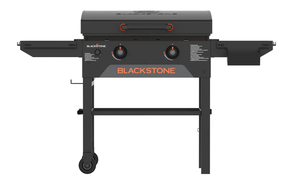 Blackstone 28-inch griddle grilling burgers and vegetables on dual heat zones with stainless hood and side shelves