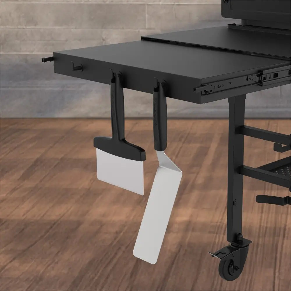 Side shelf of Blackstone 36” griddle with hanging spatula and scraper for flat top grill convenience.